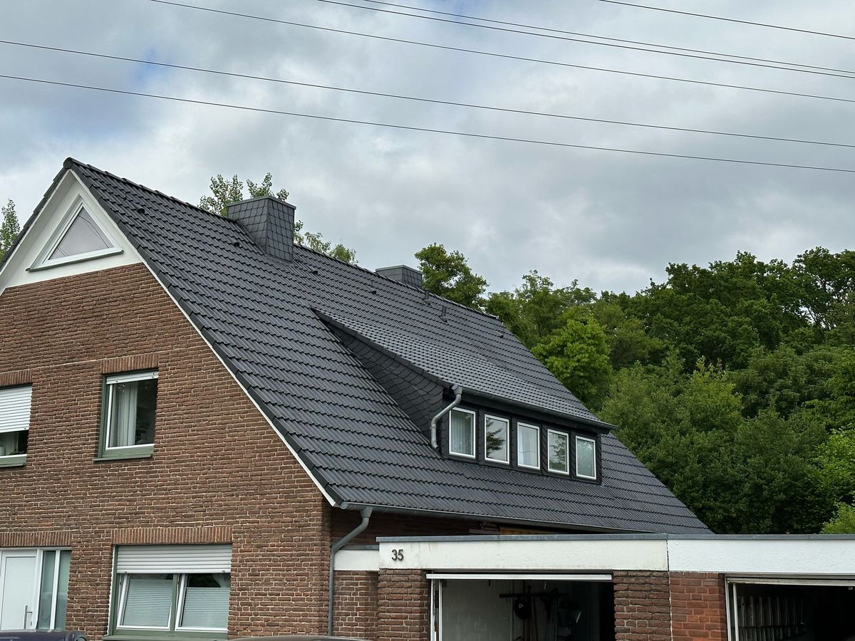 Frisch beschichtetes Dach eines Einfamilienhauses in Nordrhein-Westfalen: anthrazitfarbene Dachziegel mit geschlossener Oberfläche