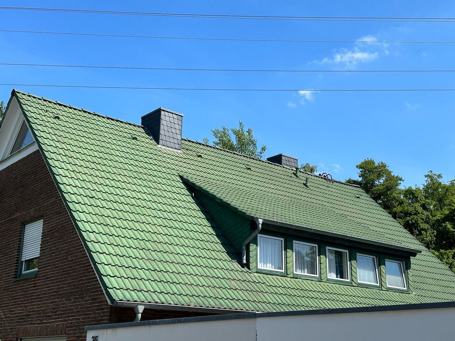 Bemoostes Ziegeldach in Münster vor der Dachreinigung – Moos zwischen den Dachpfannen